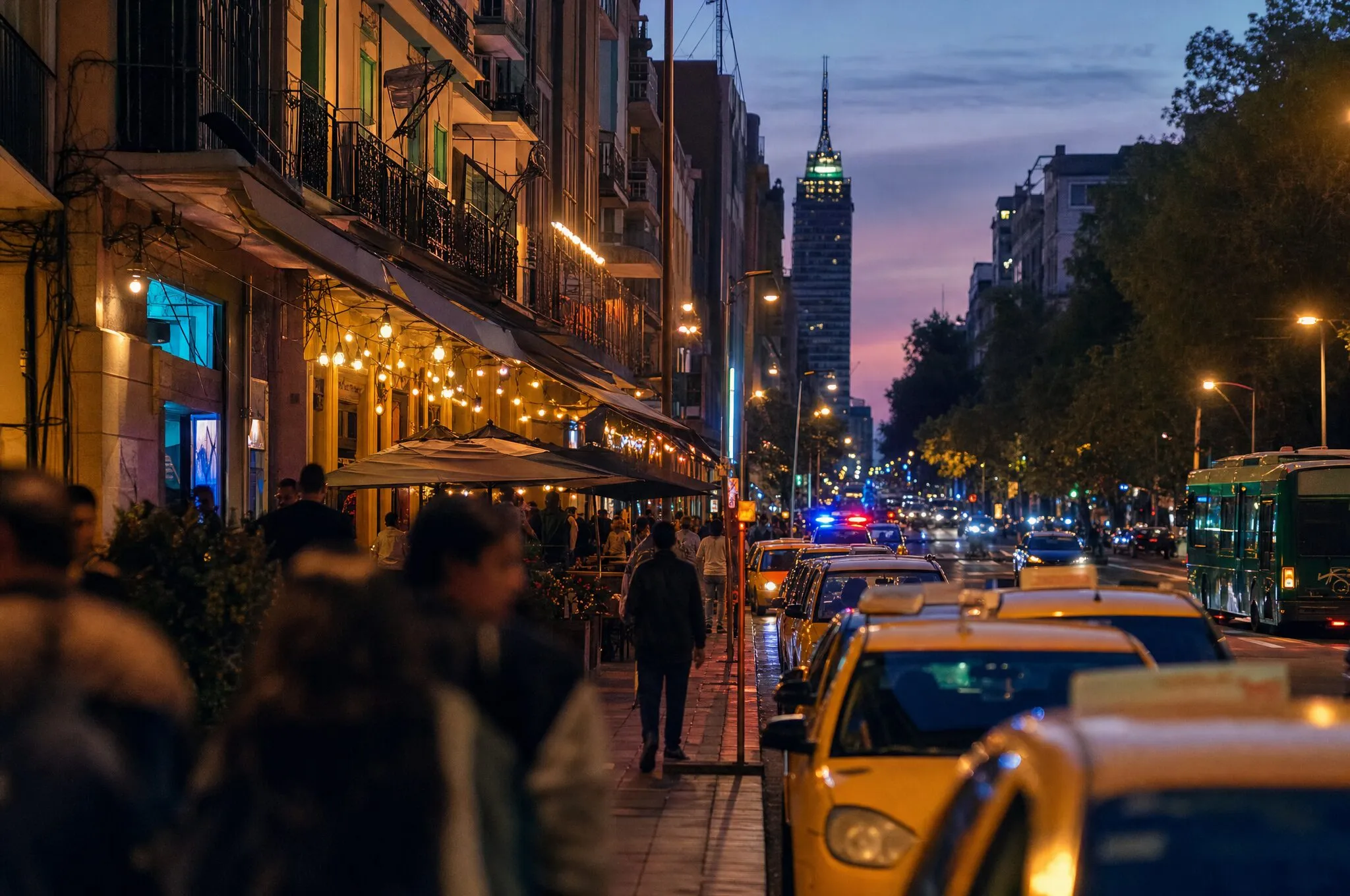 A busy nightlife avenue in Medellín at dusk, lined with taxis, bars, and pedestrians, evoking the La 70 corridor in Laureles.