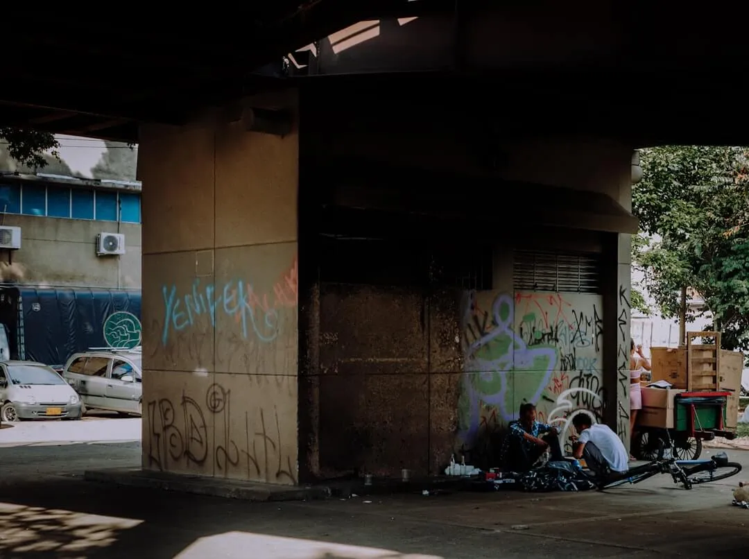 People sitting along a building wall on a Medellín street